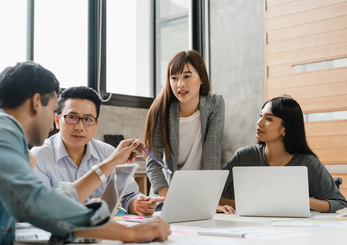 SEO strategists reviewing campaign performance around a table of open laptops